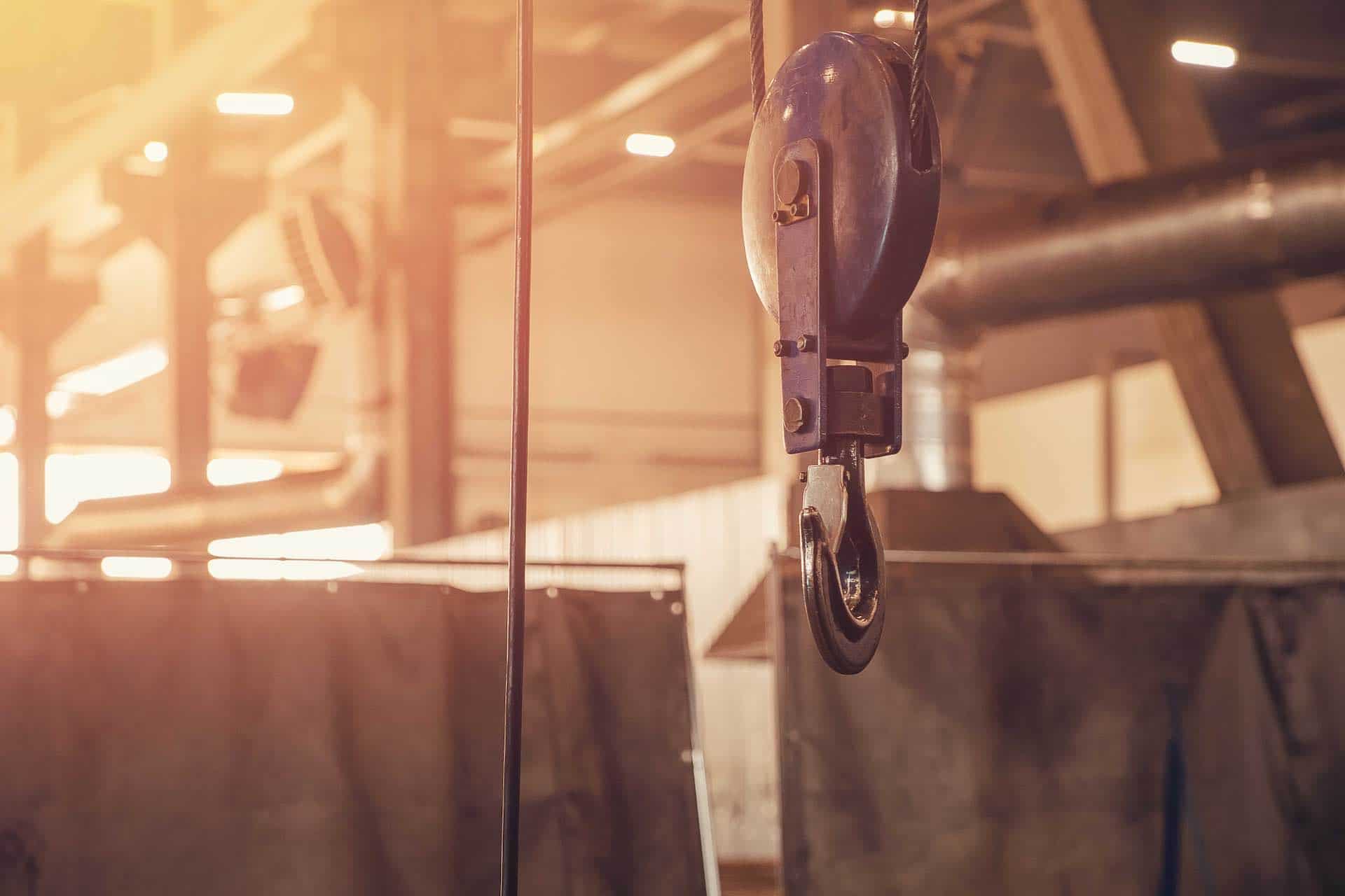 Crane chain and hook with blurred warehouse background. Concept production steel factory smeup soluzioni settore edile