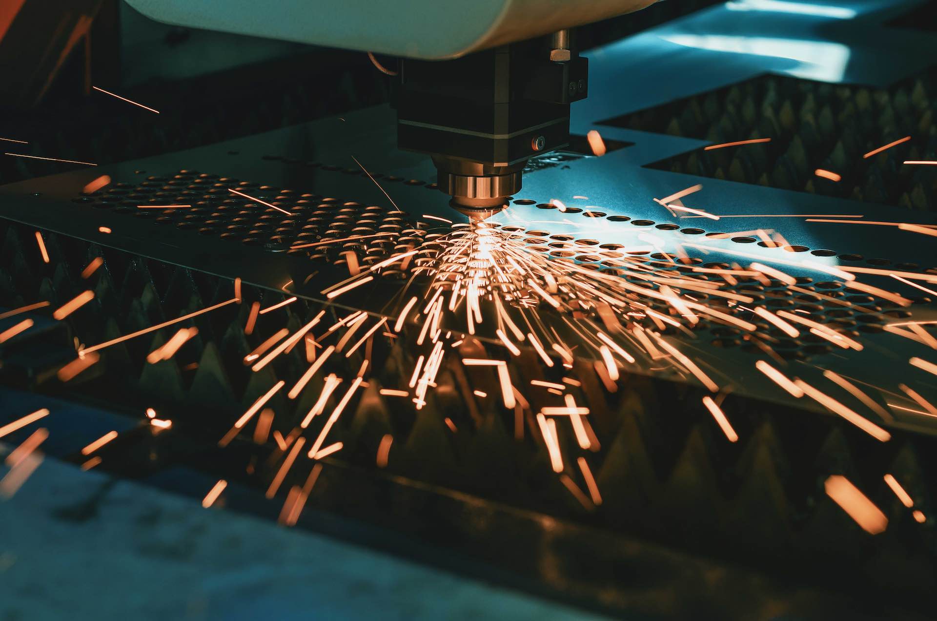 Machine for laser cutting of metal. Laser head cuts the sheet with a beam, sparks scatter in different directions smeup soluzioni settore metallurgico